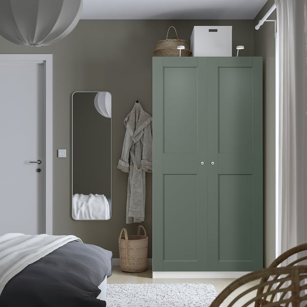 Minimalist bedroom with teal PAX wardrobe, grey linens, wicker basket, hanging robes, soft close doors.