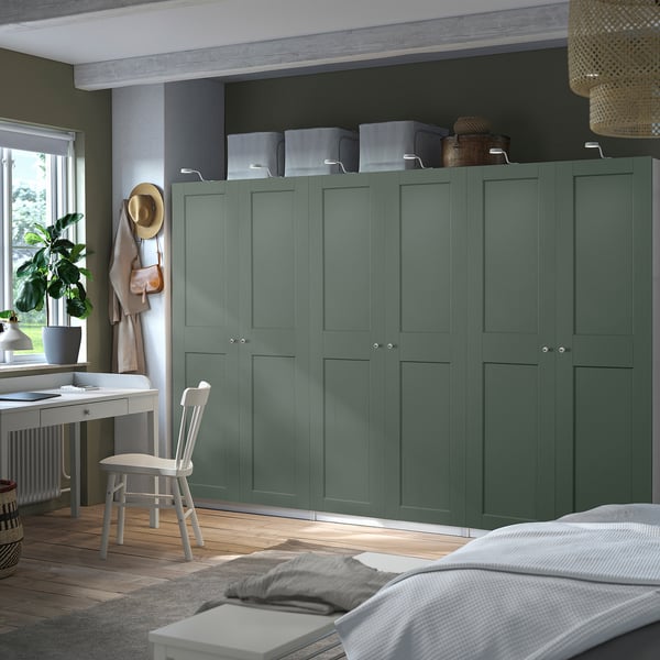 Modern bedroom tall teal PAX wardrobe, larger than nearby desk, with closed cabinets, hanging hat, basket, and white bed.