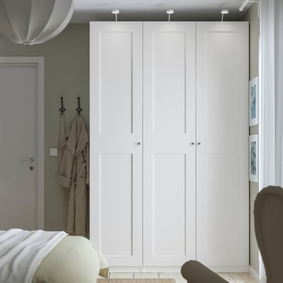 Modern white PAX wardrobe with sleek, tall doors and integrated lighting, complementing the rooms decor.