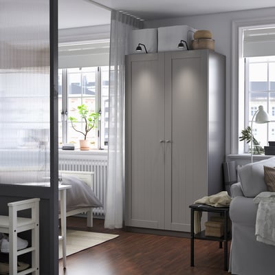 Modern living room with grey PAX wardrobe, dining set, couch, and plant.