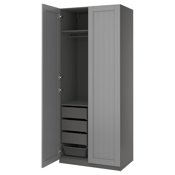A grey PAX wardrobe with open doors revealing shelves and drawers. The modern design includes adjustable feet and soft-closing hinges.