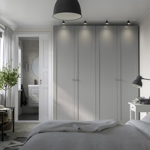 Modern grey PAX wardrobe dominates bedroom, towering beside white door, with sleek handles and integrated lighting.