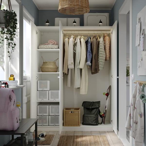 An open storage closet with hanging clothes and baskets, featuring adjustable feet, integrated lighting, and a stackable drawer system.