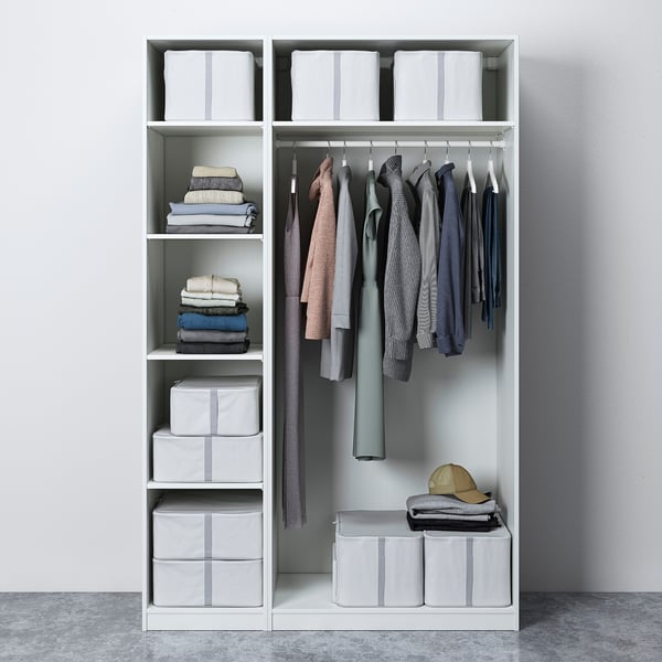 Modern closet with grey clothes, folded stacks, and striped boxes on white shelves.