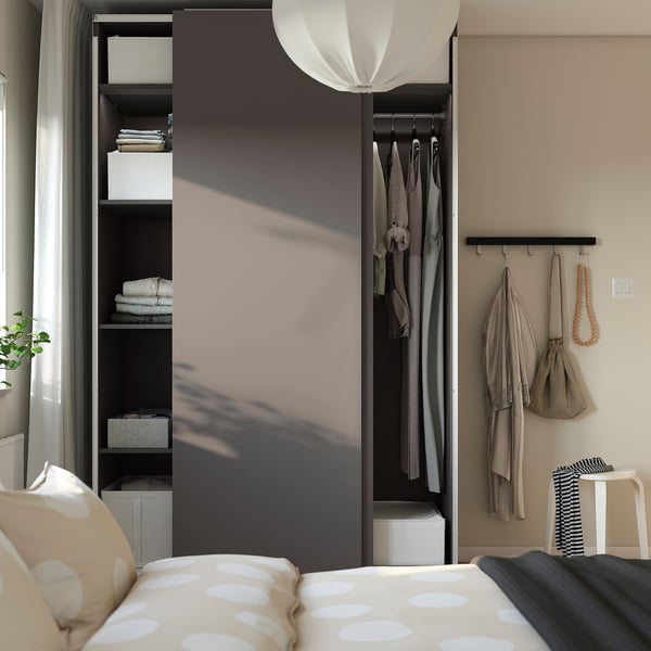 Modern bedroom with wardrobe, sliding doors, shelves, hanging clothes, organised linens, pendant light, and cosy bed with polka dot pillows.