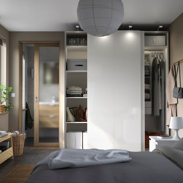 Bedroom with white PAX wardrobe, sliding doors, lighting, clothes, grey bed, wooden door, round lamp.
