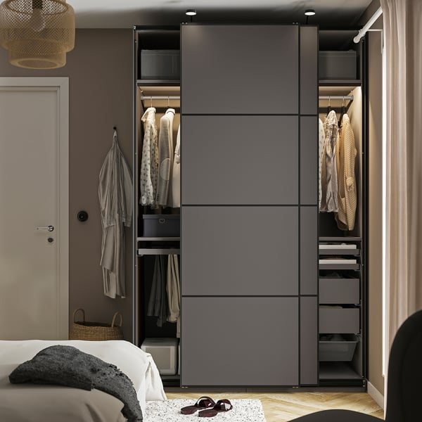 Modern bedroom featuring a tall, grey wardrobe with sliding doors, showcasing organised hangers, shelves, and drawers for efficient storage.