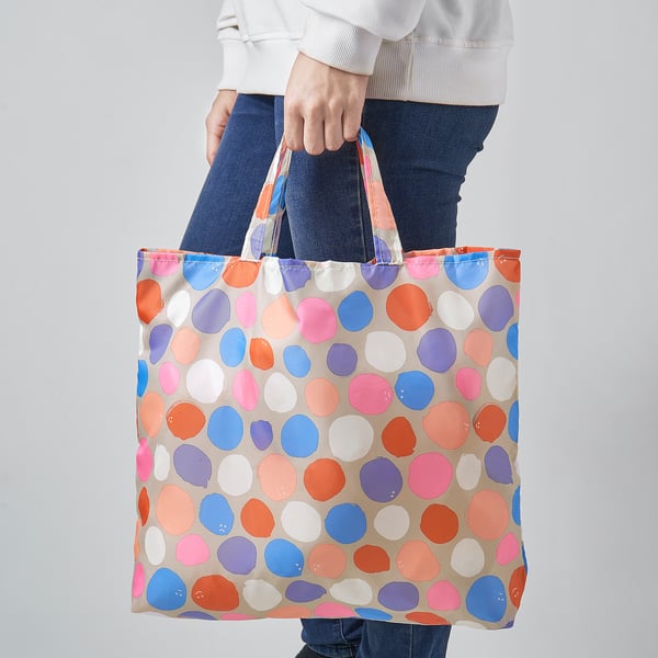 Person holding a colourful polka-dot tote bag.