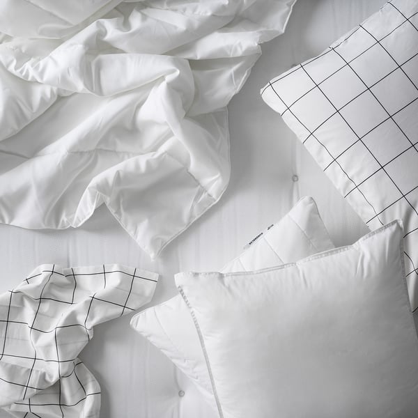 A white SÄFFEROT duvet and pillowcases made of recycled polyester, featuring a grid pattern design laid out on a bed.
