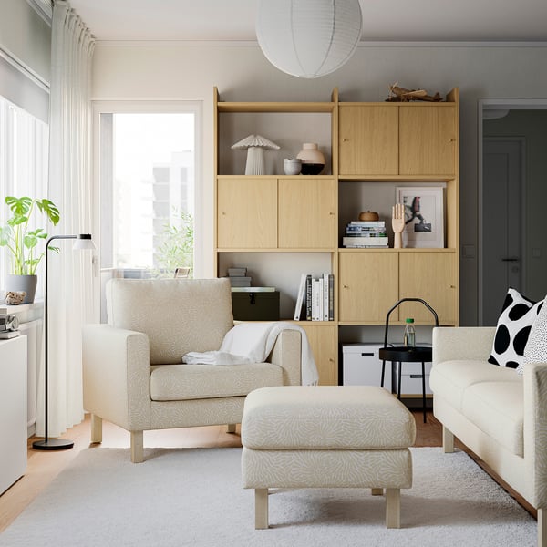 Minimalist living room with SALTSJÖBADEN footstool, rug, bookshelf, lamp, plant, and side table.