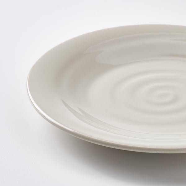 Close-up of an off-white plate with a subtle, rustic texture and gentle waves, set against a plain white background.