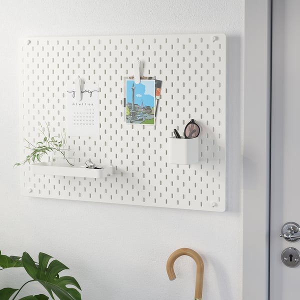 White wall organiser with hooks, cups, and calendar.
