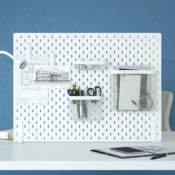 SKÅDIS white pegboard organiser with mesh pockets and drawings on a blue wall, larger than the items on the table.