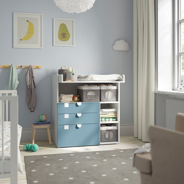 Baby room with light blue SMÅSTAD changing table, grey rug, white walls, and colourful decor.