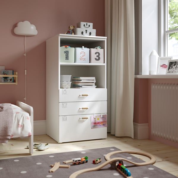 White SMÅSTAD kids bookcase with drawers beside bed, storing books, toys, and crafts.
