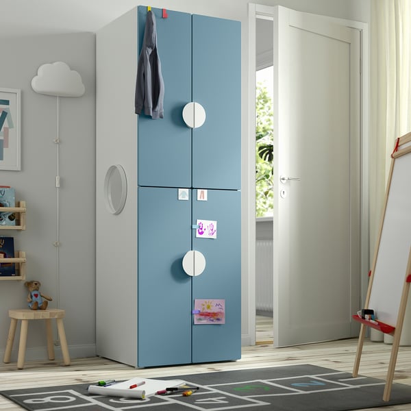 Childs room with blue SMÅSTAD wardrobe, large, near door, hanging coat, with drawers, stickers, art supplies.