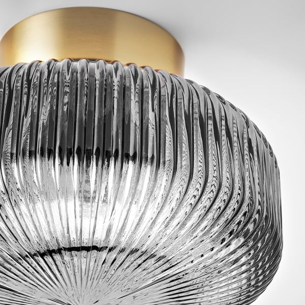 Modern pendant lamp with ribbed glass shade and gold top, emitting soft light.