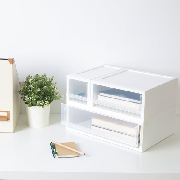 Pratt white storage drawers, stacking neatly, clear pulls, holding books, small potted plant nearby, simple design.