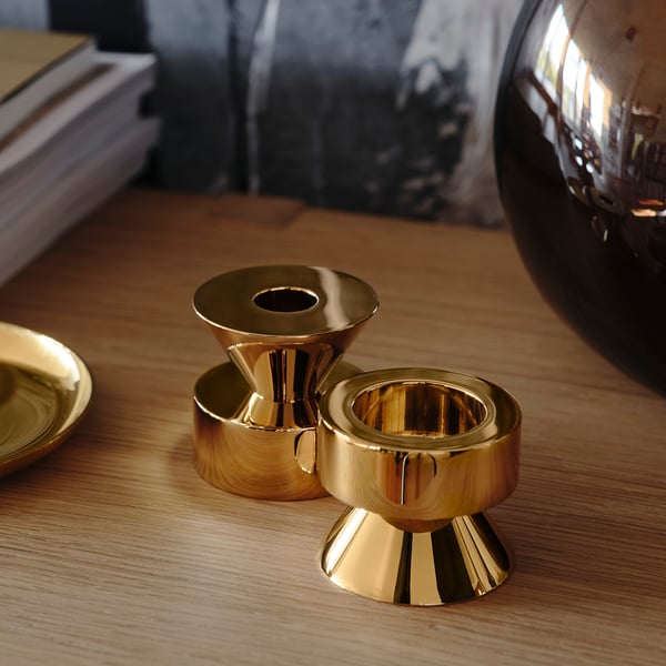 Three golden candlesticks on a wooden table; two upside down, one right side up, reflecting high-quality metal finish and sturdy design.