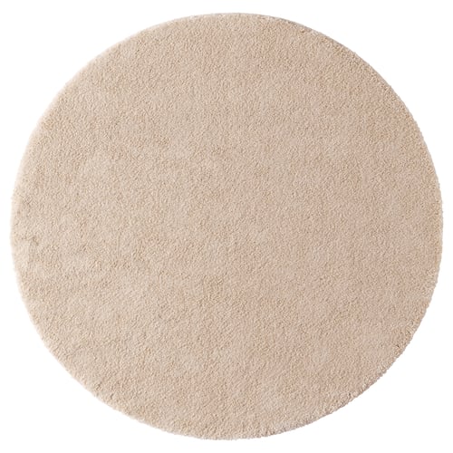 A tan-colored, round area rug with a soft pile, featuring a gentle sheen and recycled materials.