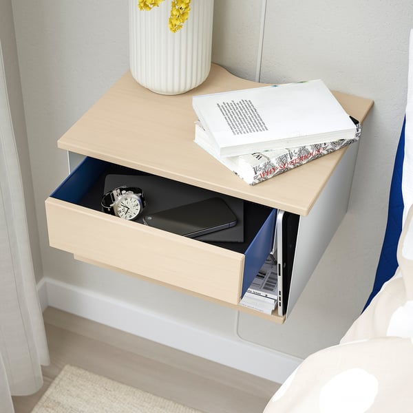 Modern wall-mounted bedside table with open storage for books and a drawer for personal items, featuring cable cut-outs for convenience.
