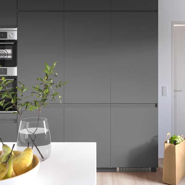 Modern kitchen with large grey fridge, sleek cabinets, and produce.