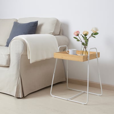White SVENARUM side table with bamboo tray, roses, and cup next to beige couch.