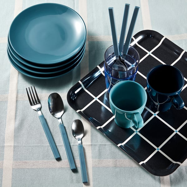 Teal plates, cups, blue cutlery on chequered mat.