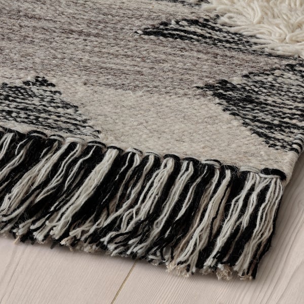 Handwoven moroccan-style rug with long fringes, showcasing intricate patterns & soft, durable wool texture.