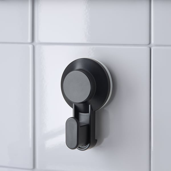 Black suction cup hook on white tiles, securely hanging items up to 3 kg.