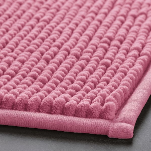 A close-up of a pink bath mat, showcasing its soft, textured surface and plush, inviting quality.