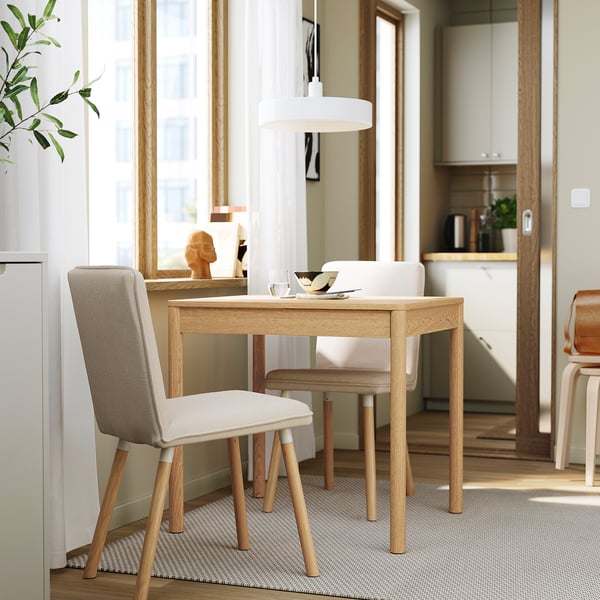 Modern dining area with TONSTAD table, extending to fit multiple chairs; sleek light wood finish, large window with curtains.