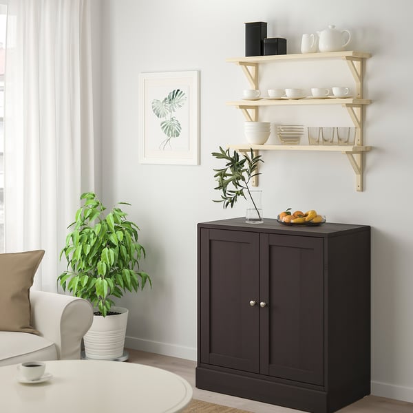 Modern dining area with TRANHULT cabinet and wooden shelves holding white dishes. Plant and cup on table.