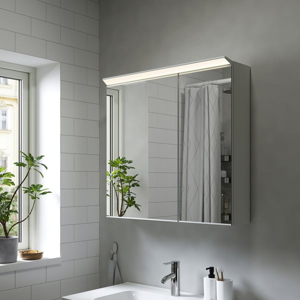 Modern bathroom with TREASJÖN mirror cabinet, led lighting, plant reflection, clean style.