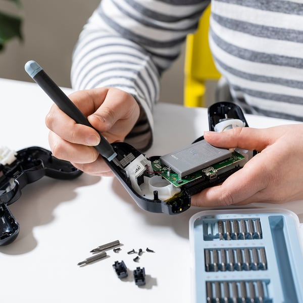 Person fixing electronic device with TRIXIG screwdriver.