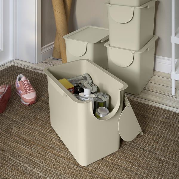 Three beige TRÖSKNING bins, with the front one open showing recycling items inside. Stacked for space-saving and sorting waste.