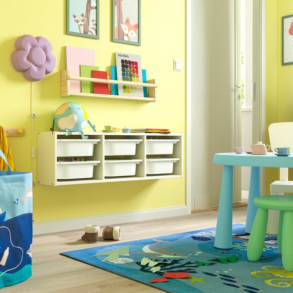 Kids playroom with TROFAST shelves, colourful toys, and blue table setup.
