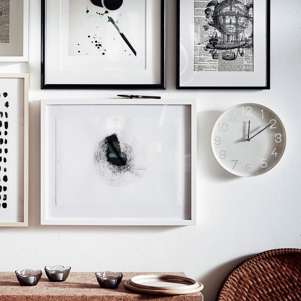 Modern clock with white face and black hands, art, nautical-themed table setup.
