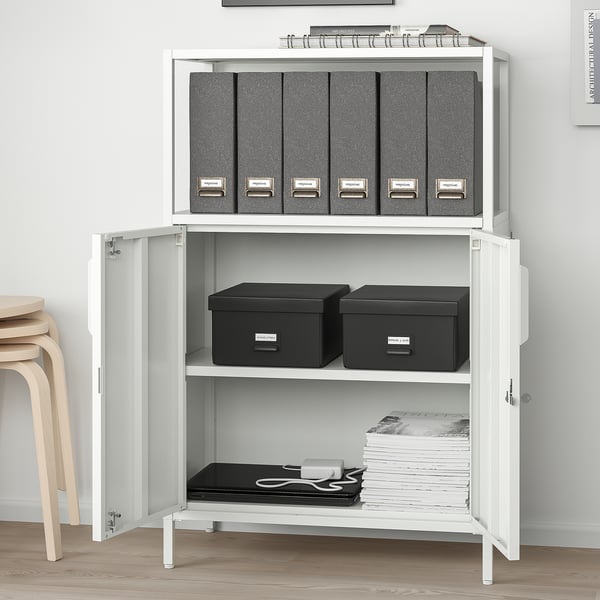 White cabinet with grey folders, black boxes, and paper stacks. Wall-mounted, adjustable shelves.