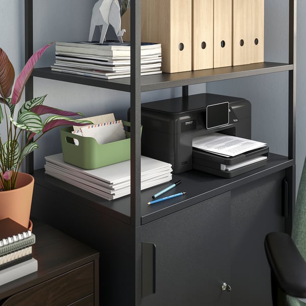 A TROTTEN black double-sided office cabinet with open and closed storage, a printer, and a plant.