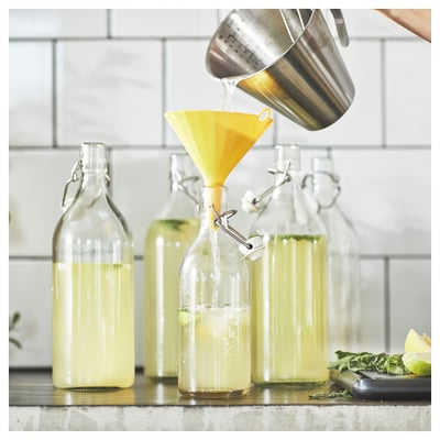Kitchen funnel filling bottles. Clamped bottles near limes.