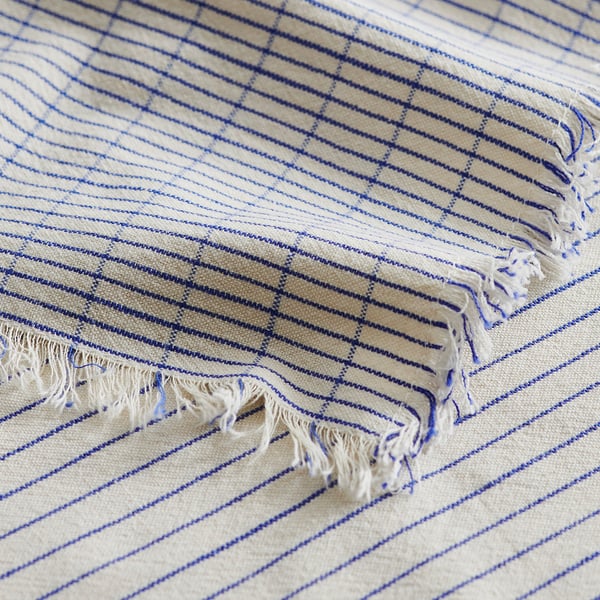 Close-up of VÄLVÅRDAD towel: cream background, blue stripes, fringes; shows texture & quality.