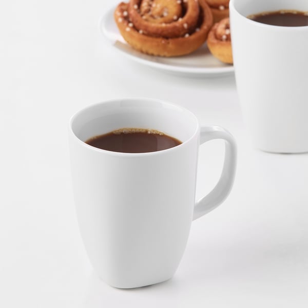 Two white mugs of coffee with pastries; durable, impact-resistant feldspar porcelain.