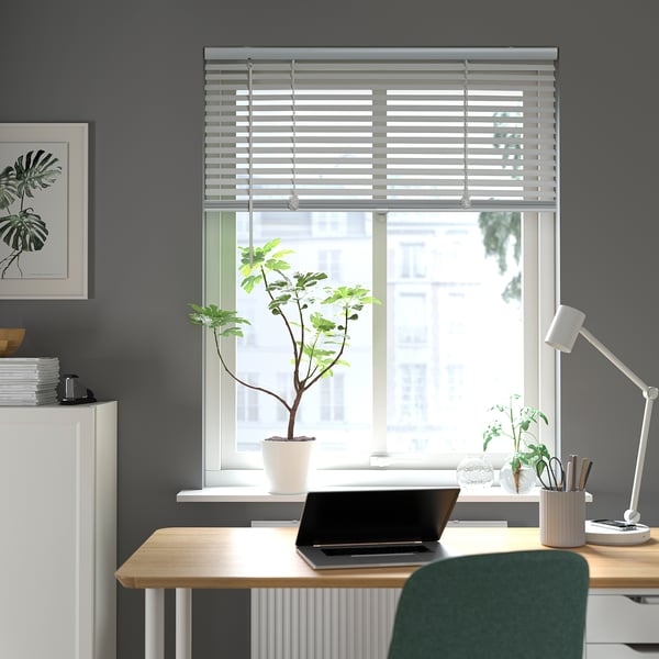 Modern office with VECKLARFLY blinds, desk, laptop, plant, green chair, grey walls, art, lamps.