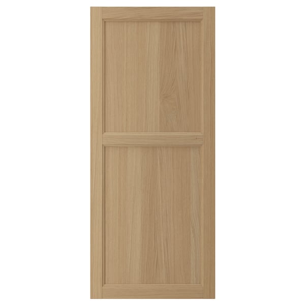 A VEDHAMN wooden door in a light oak finish. It has a solid oak frame with oak veneer panels, featuring a simple yet elegant design.