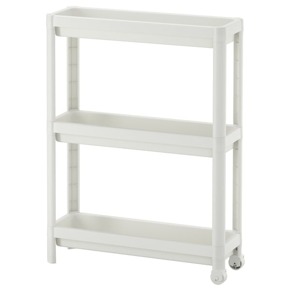 A white VESKEN storage trolley with three shelves, designed for narrow spaces, featuring a stable and mobile structure with wheels.