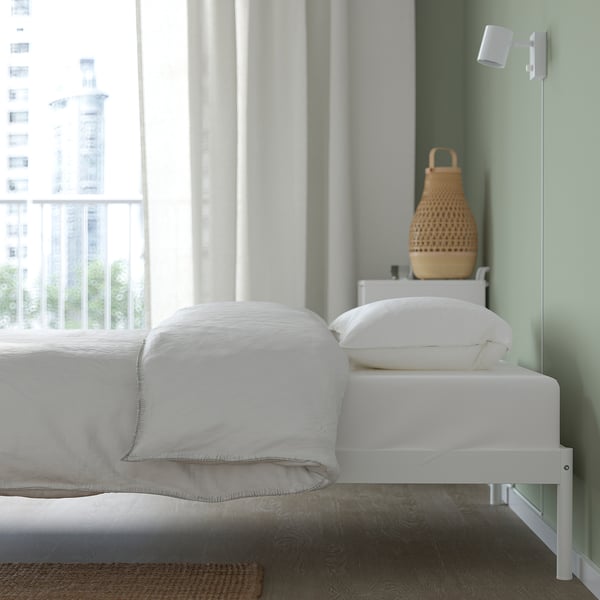 Minimalist bed frame with slatted base for storage under. Modern design with visible screws and vacuum-friendly space.