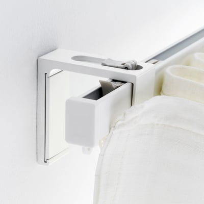 Wall-mounted curtain bracket. Holds rail close to wall, blocking light for better sleep.