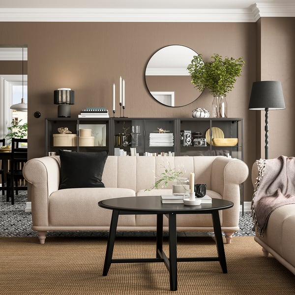 Modern living room with beige VISKAFORS sofa, black coffee table, black and white decor, round mirror, plants, and floor lamp.