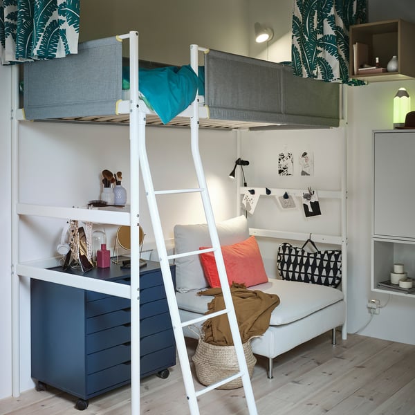 Bedroom with VITVAL white bunk bed, blue comforter, ladder, drawers, shelves, couch, pillows, walls with leaf design.